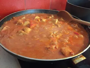 A frying pan filled with chunky, wet enchilada filling.