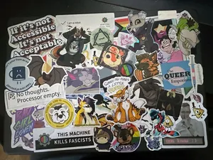 A top-down photograph of a laptop that has been sticker bombed with dozens, if not hundreds, of stickers.